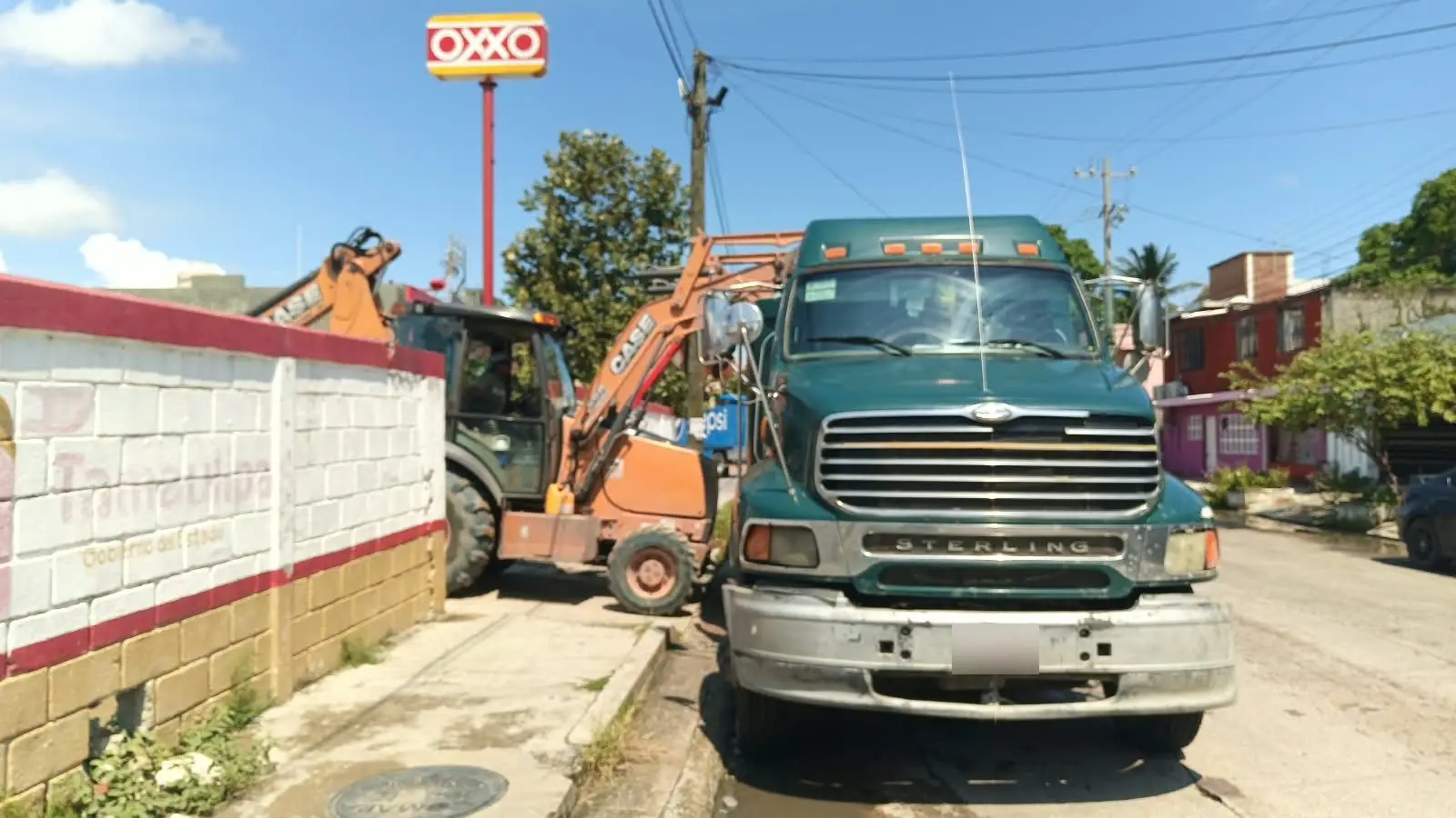Camión de volteo Sterling estacionado junto a una retroexcavadora Case